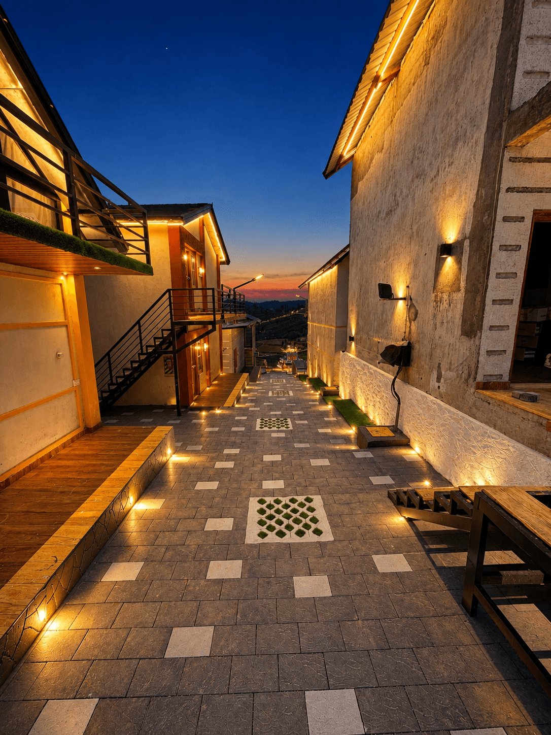 Illuminated paved walkway between hillside villas